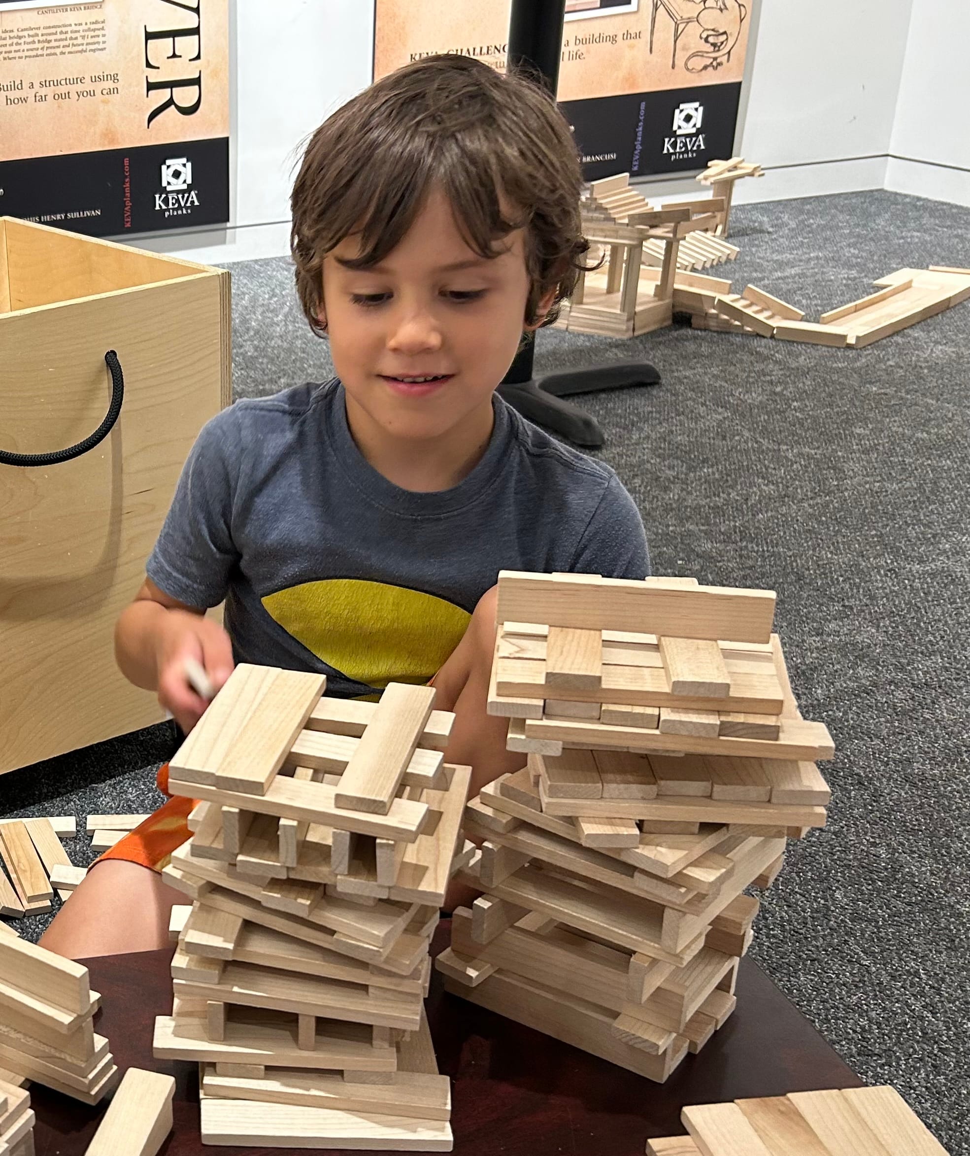 A young child builds towers with Keva planks.