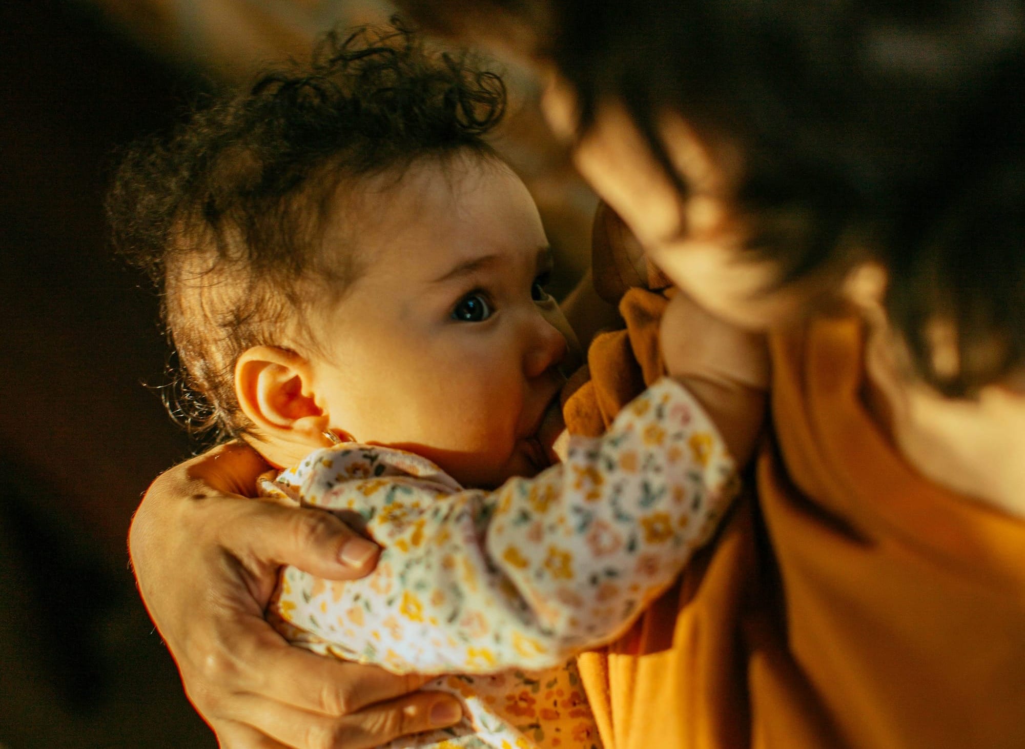 A nursing baby and its mother make eye contact.