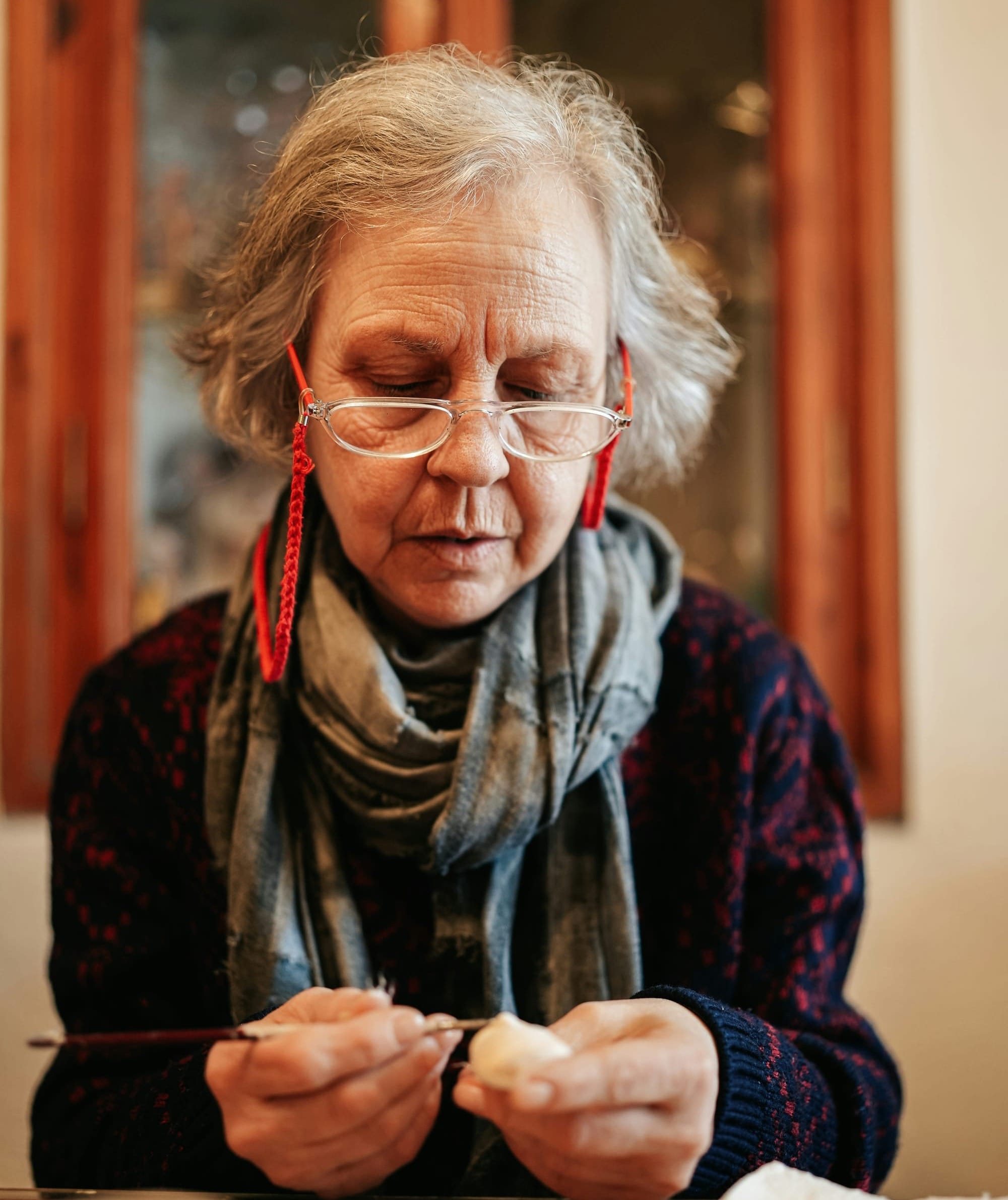 A older woman works carefully on a craft project.