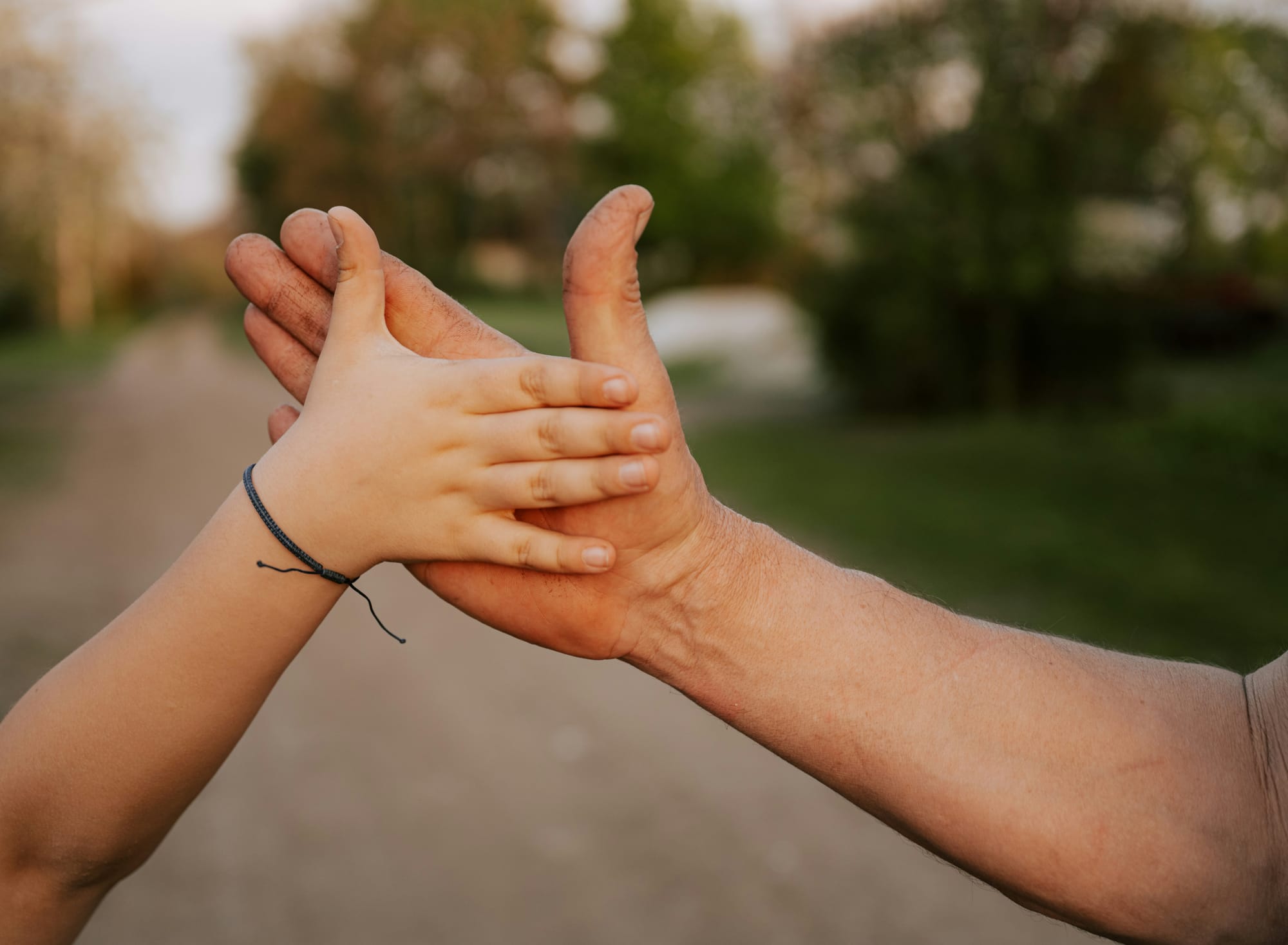 A child's hand, thumb outspread, touches an adult's in same position. Moment of recognition?