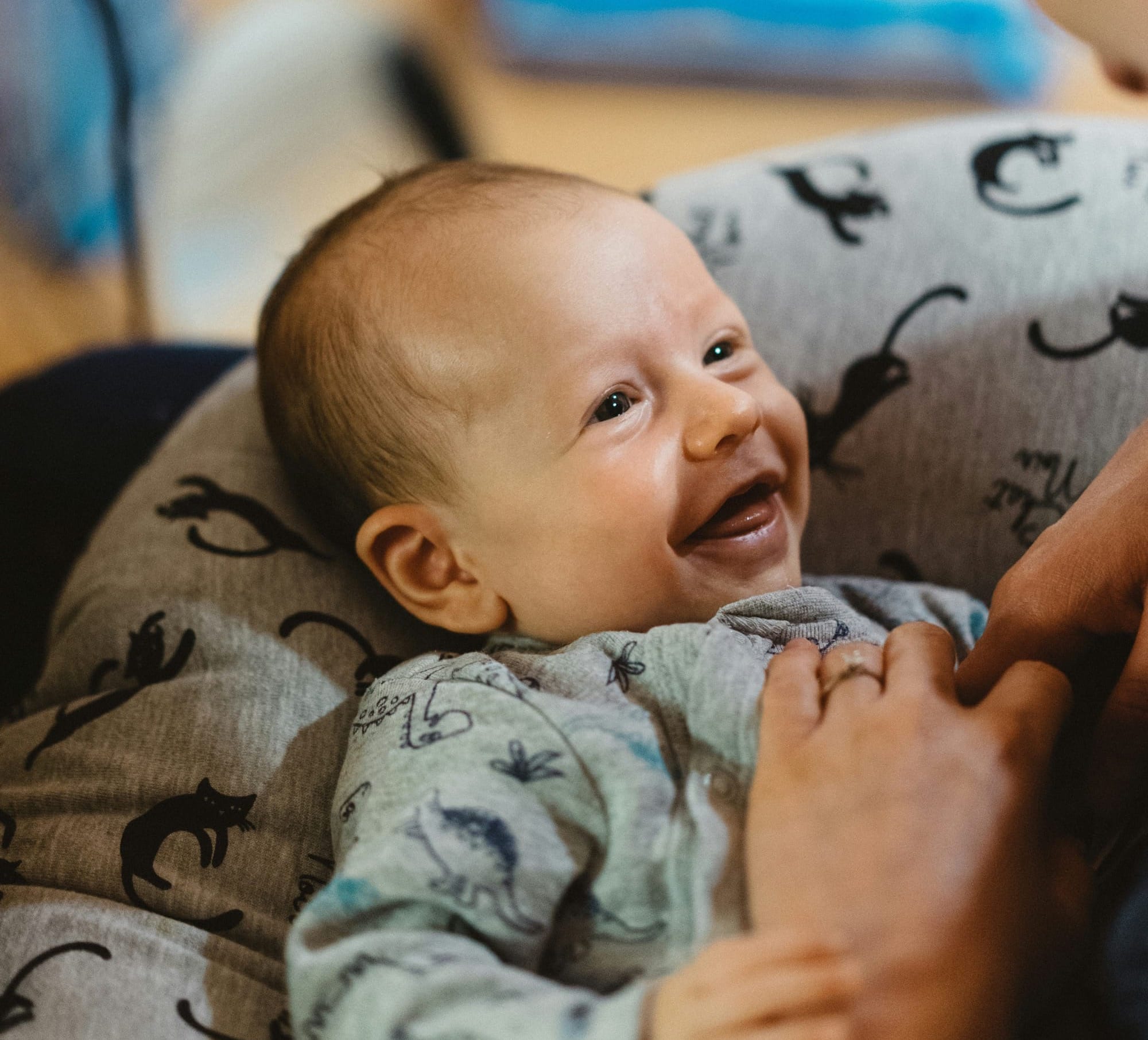 A baby smiles widely at its caregiver. 