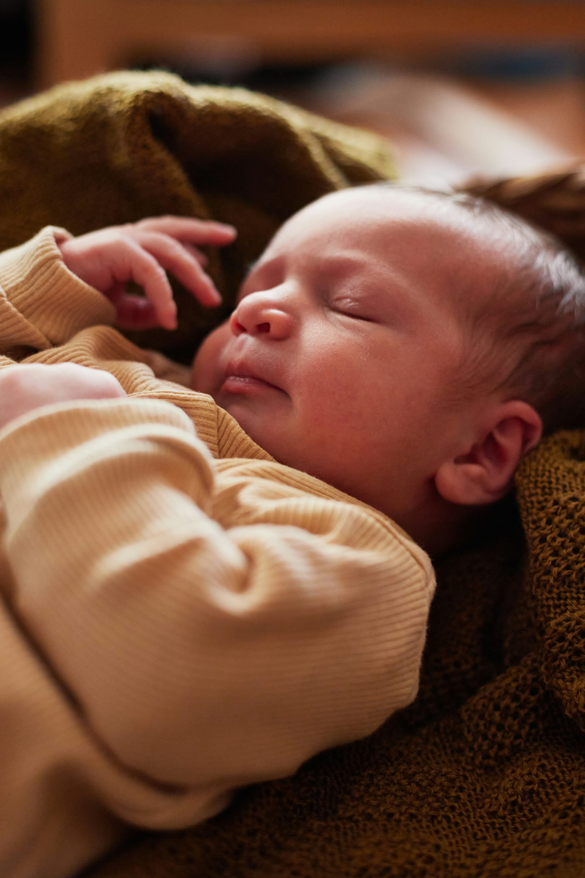 A sleeping newborn on a blanket.